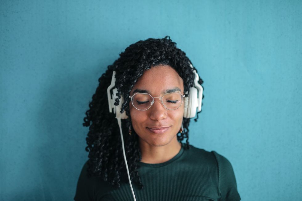 woman in glasses wearing headphones against a blue background