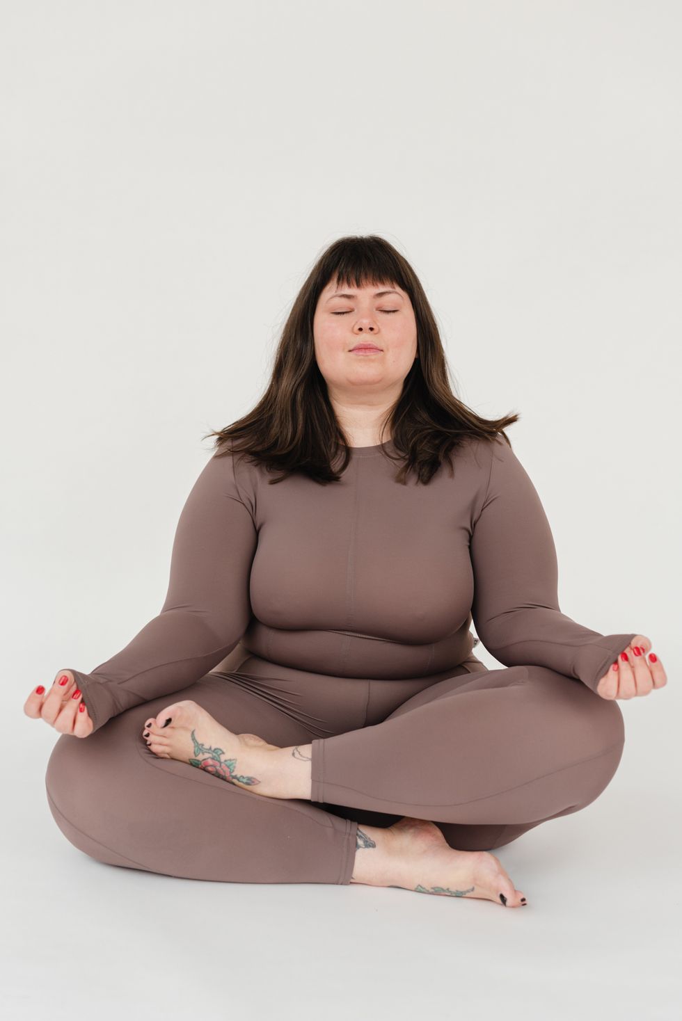 woman in matching set meditating, Best Workouts for Cycle Syncing