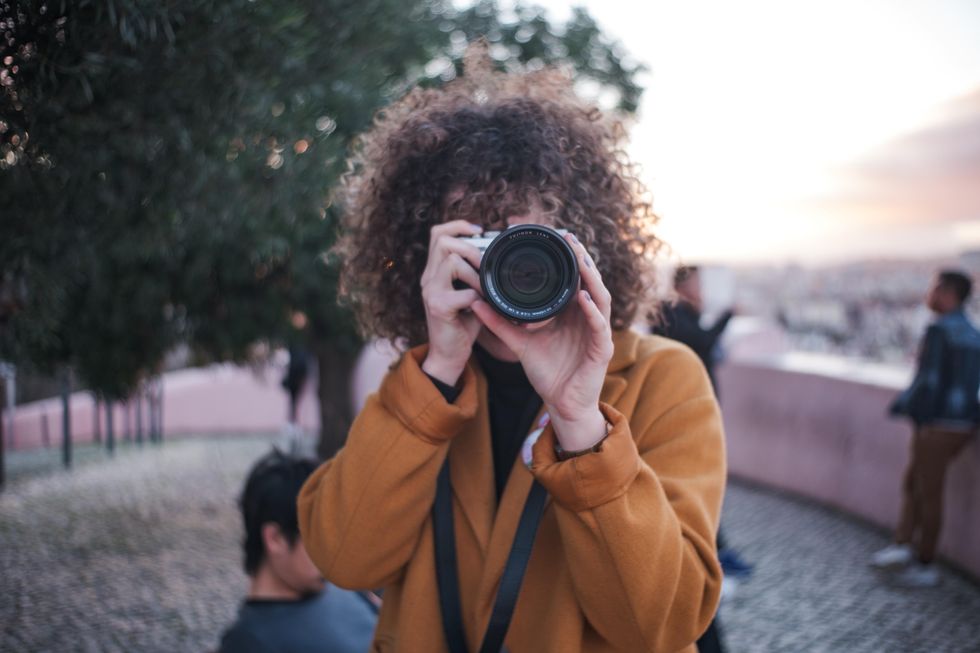 woman in orange jacket holding camera