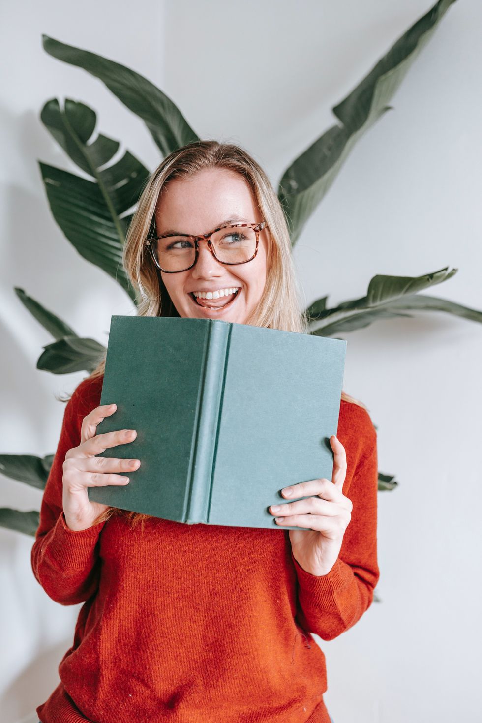 woman in red sweater holding up a book