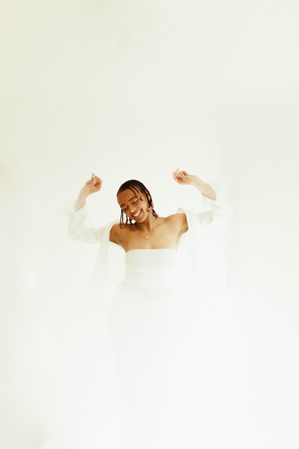 woman in white dress with arms up dancing happy