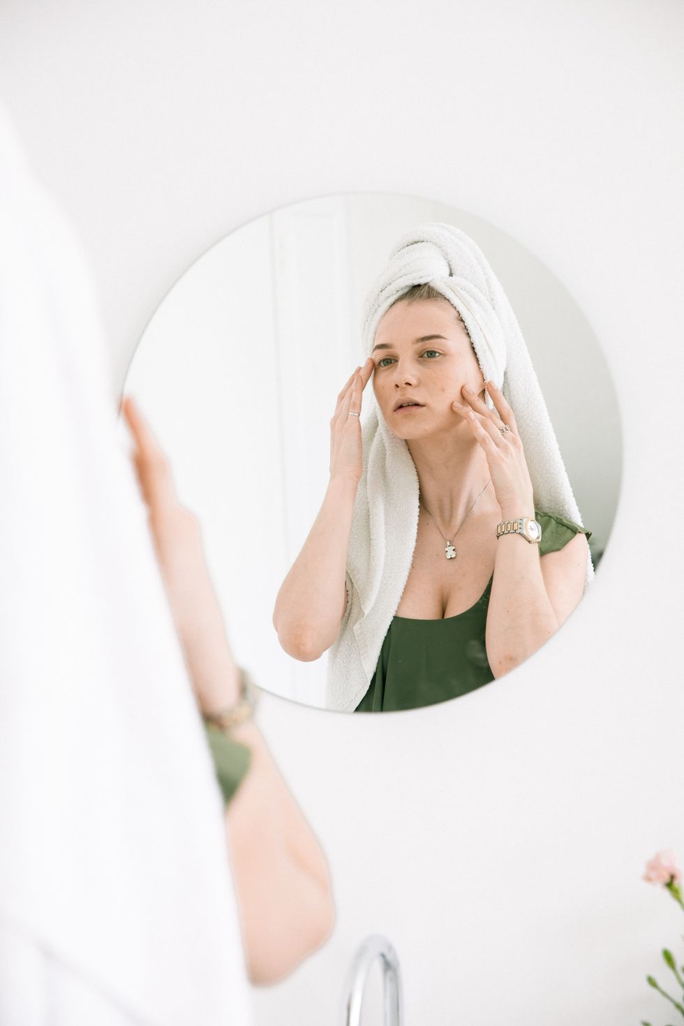 woman looking in the mirror, touching her face for lymphatic massage