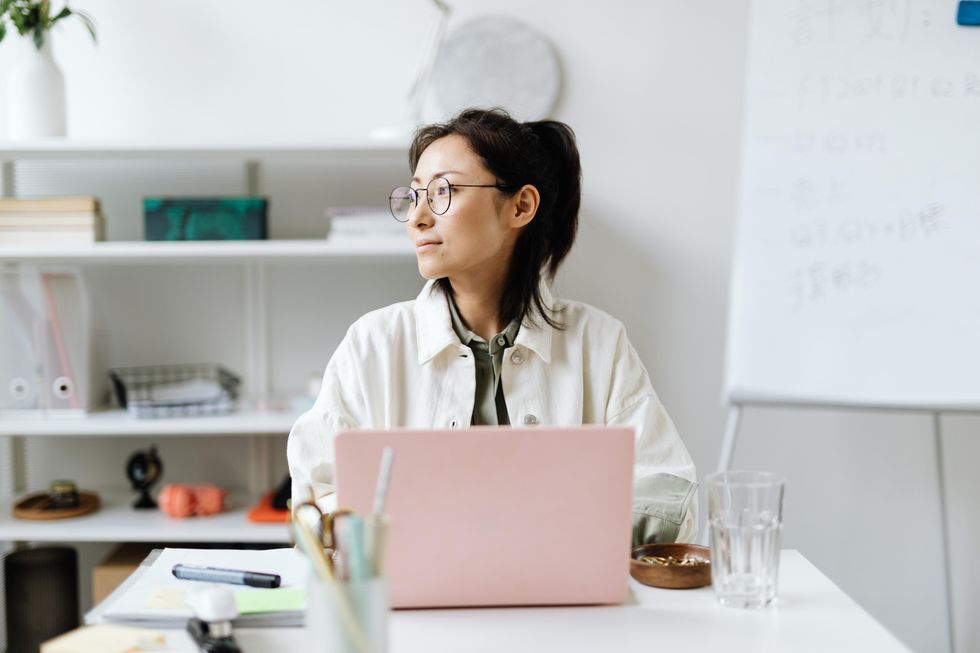 Woman on laptop looking away from screen writing typing