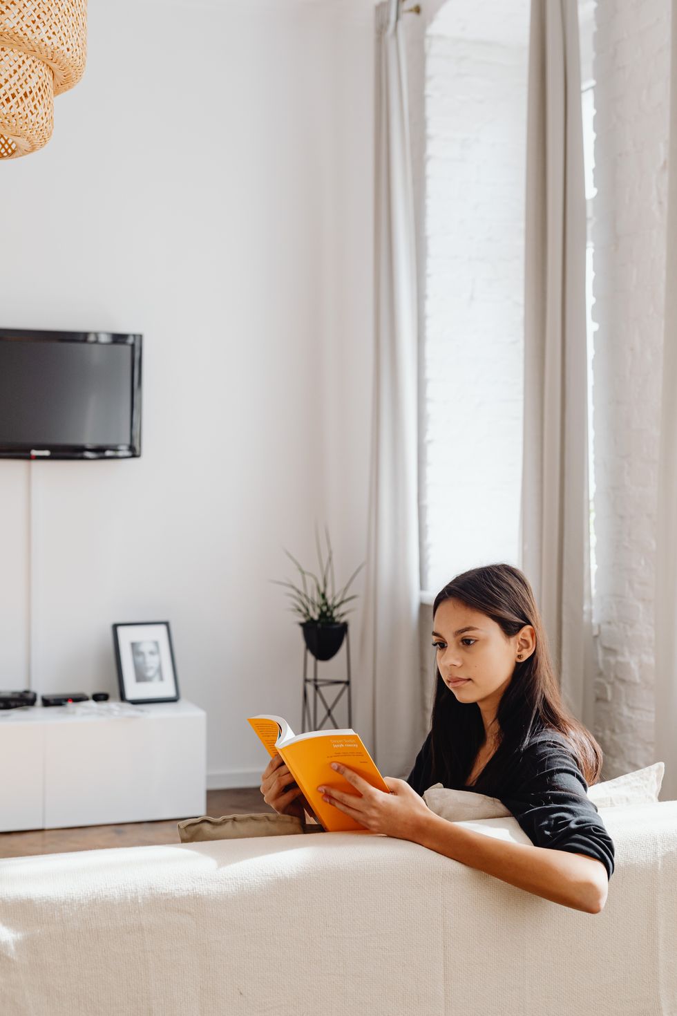 woman on sofa reading a book inside