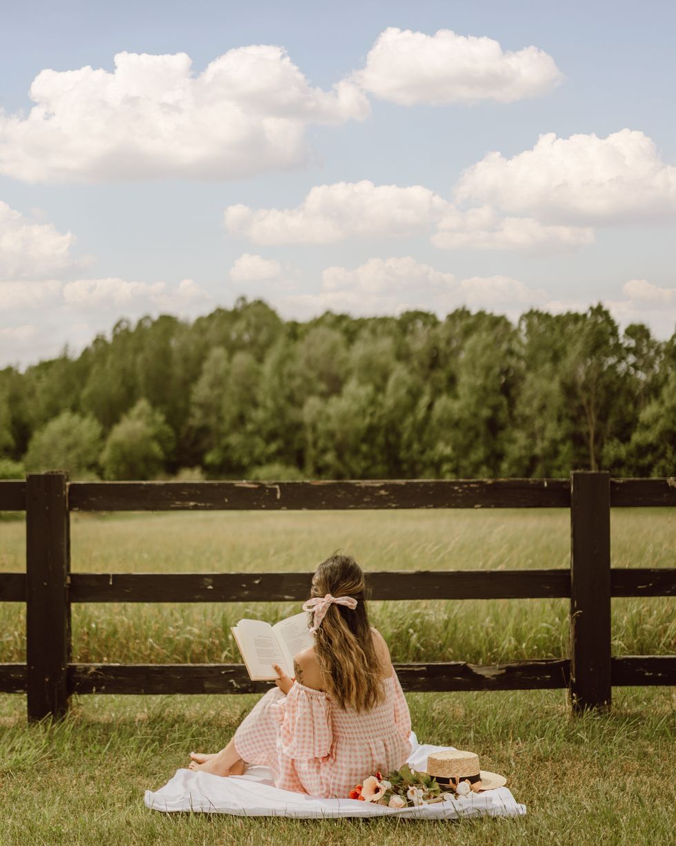 woman reading a book in a grassy field