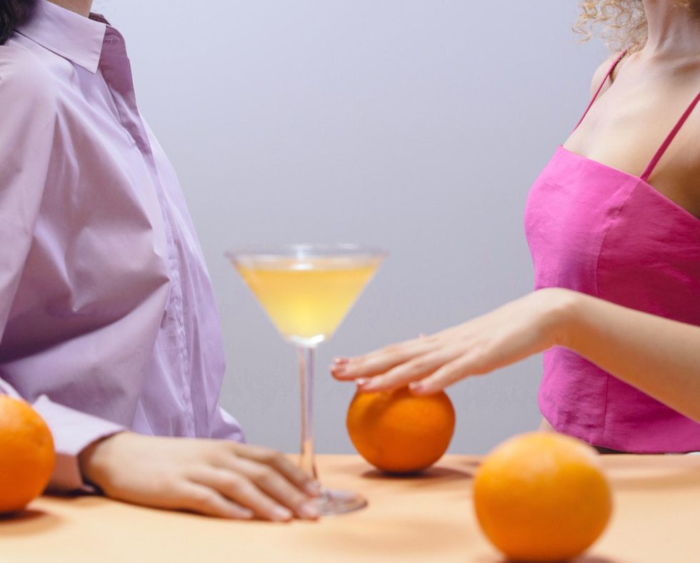 woman rolling orange on countertop with cocktail glass