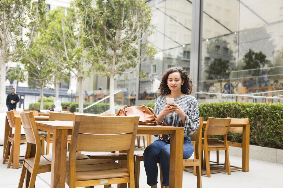 woman sitting at a table on her phone