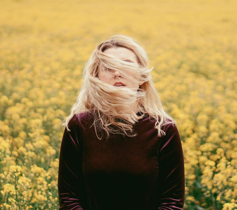 woman standing in a field of yellow flowers