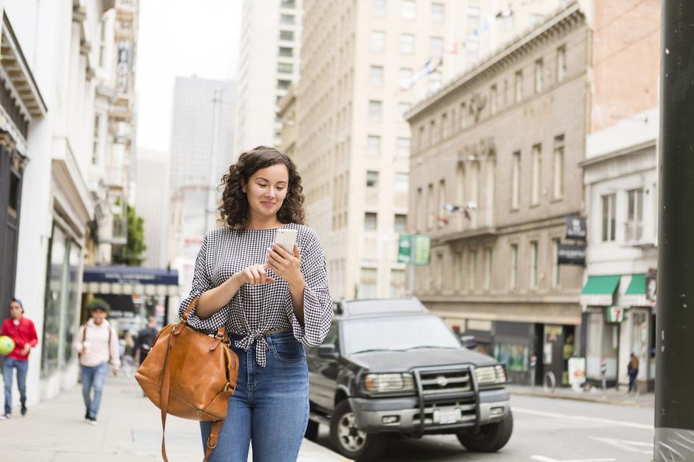 woman walking through the city looking at her phone