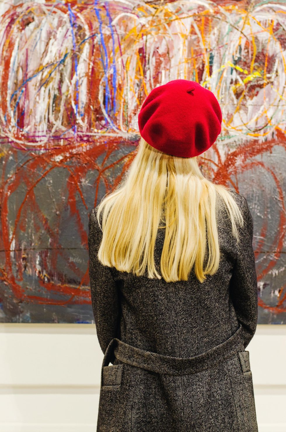 woman wearing a beret looking at a painting