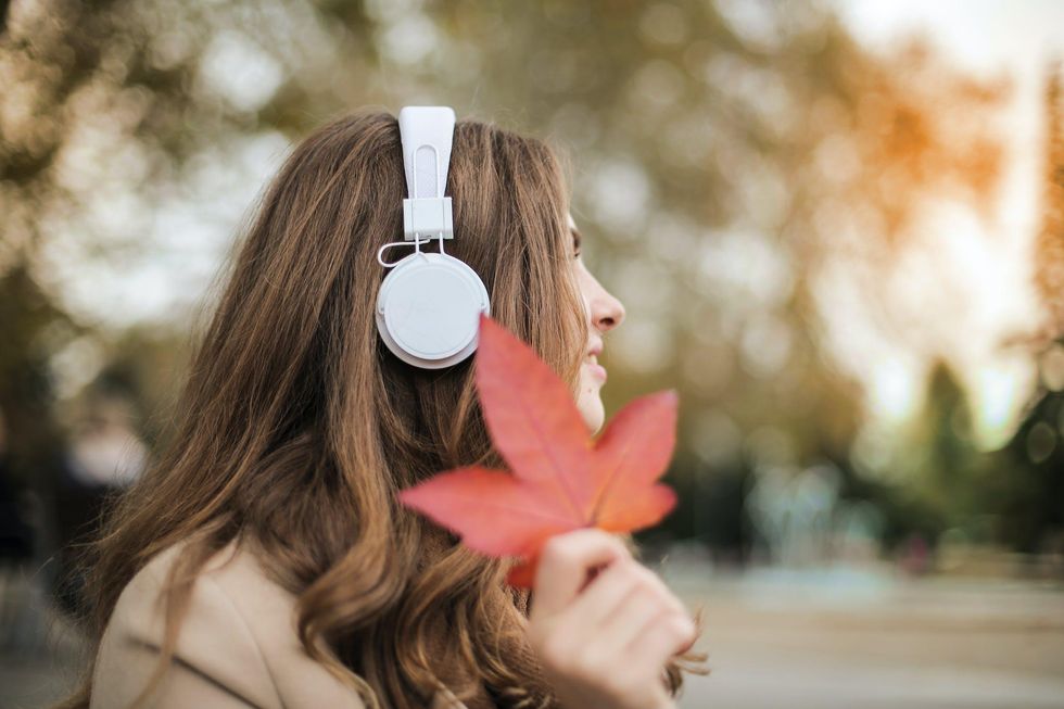 woman wearing headphones listening to music and holding a leaf