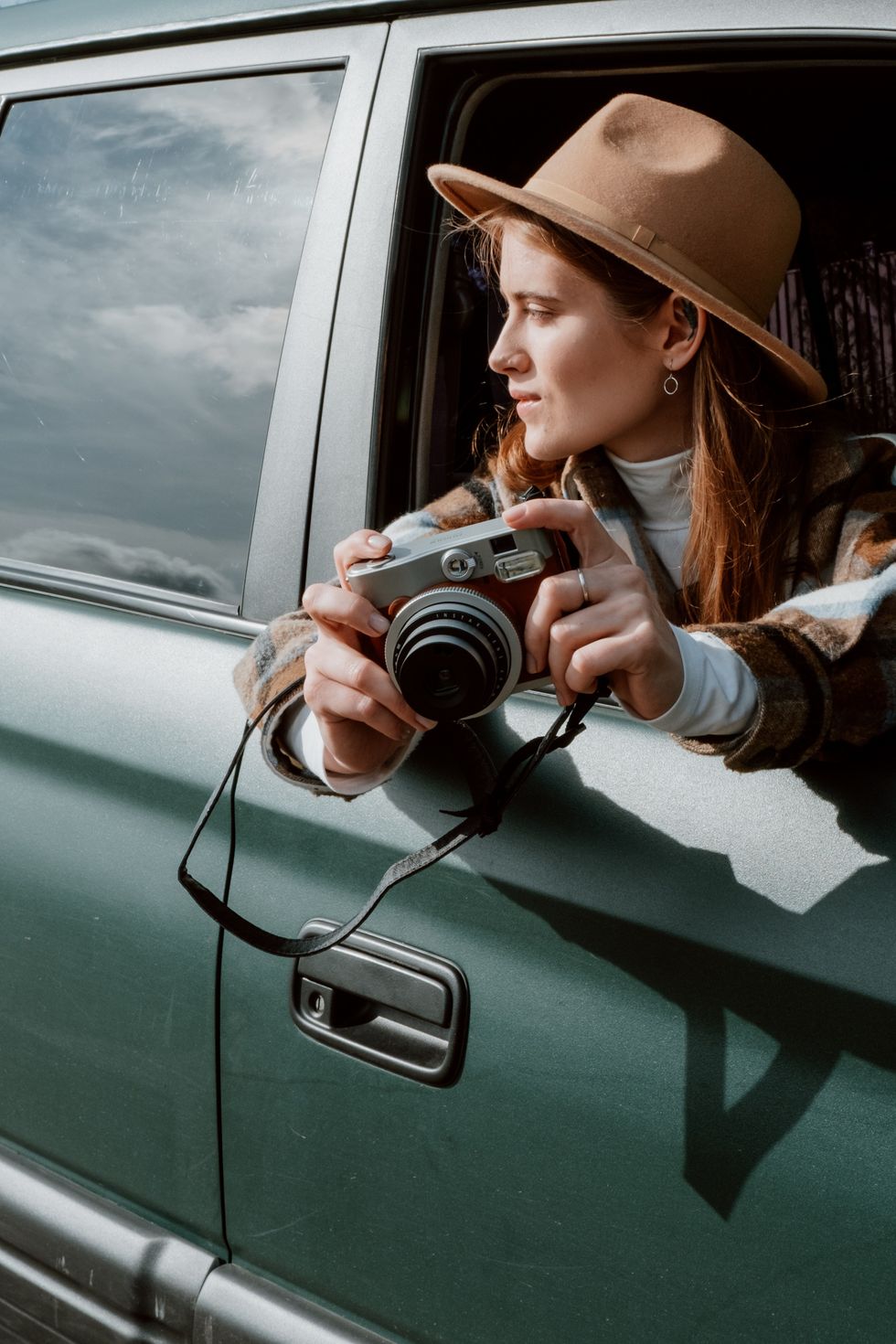 woman with camera looking out car window