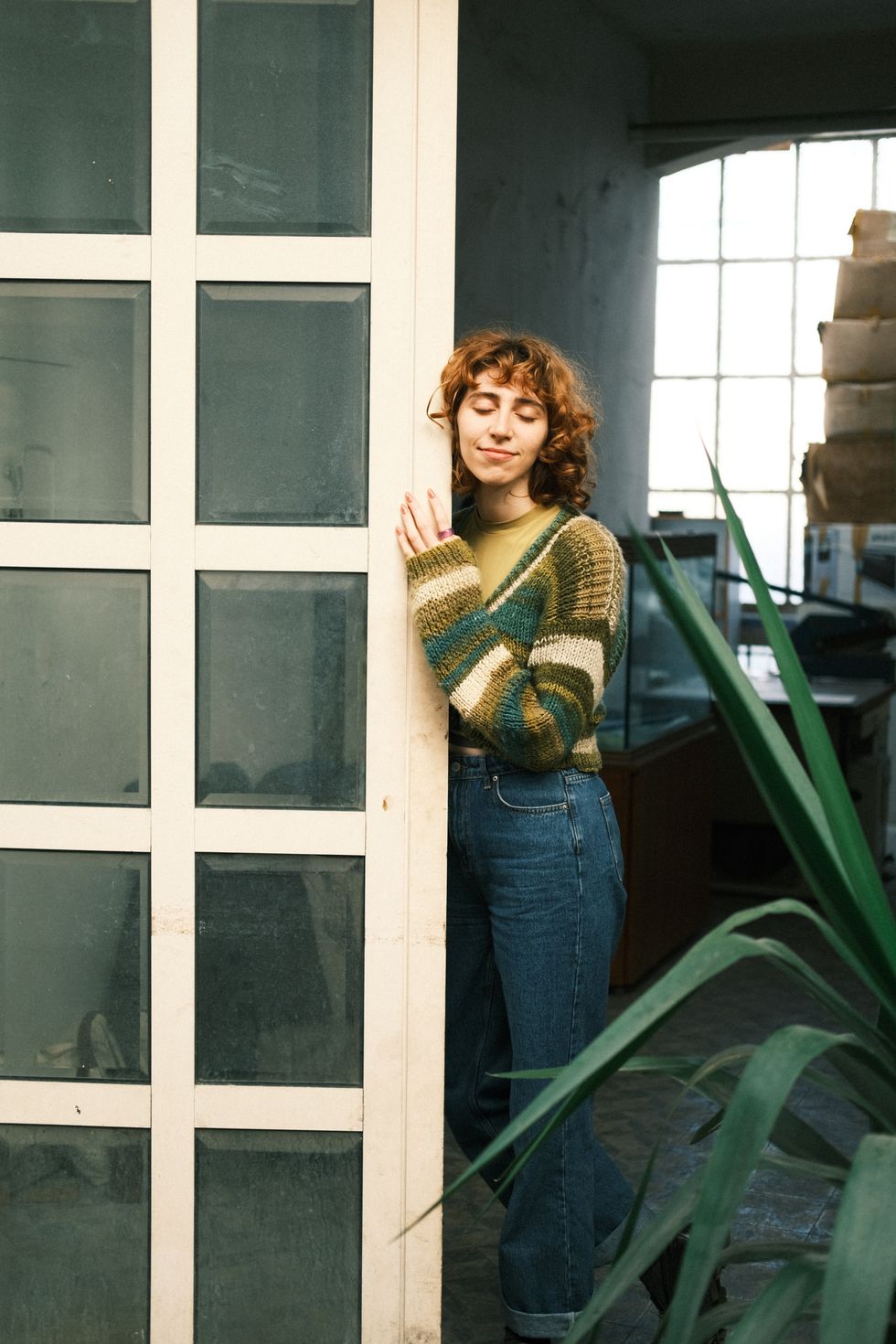 woman with eyes closed leaning against a door