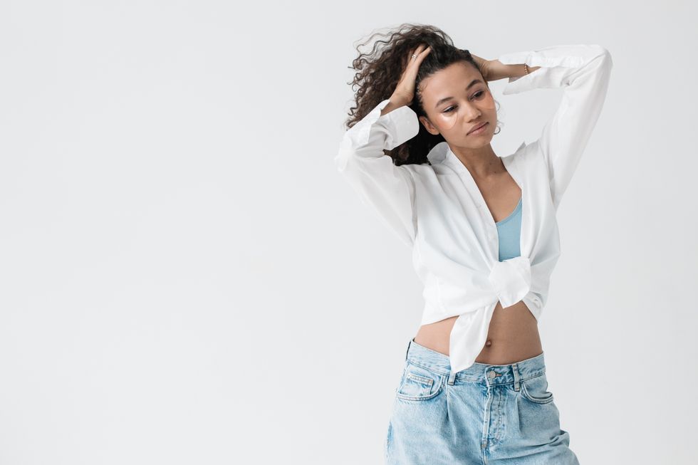 woman with white shirt and jeans hands in her hair