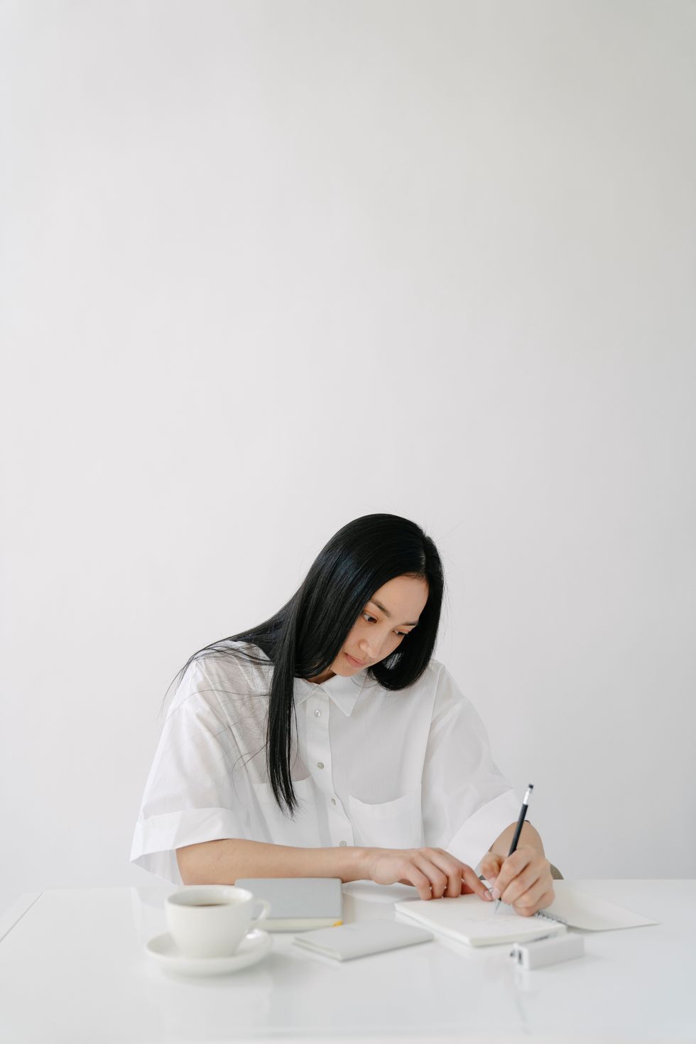 woman writing on notepad in all white