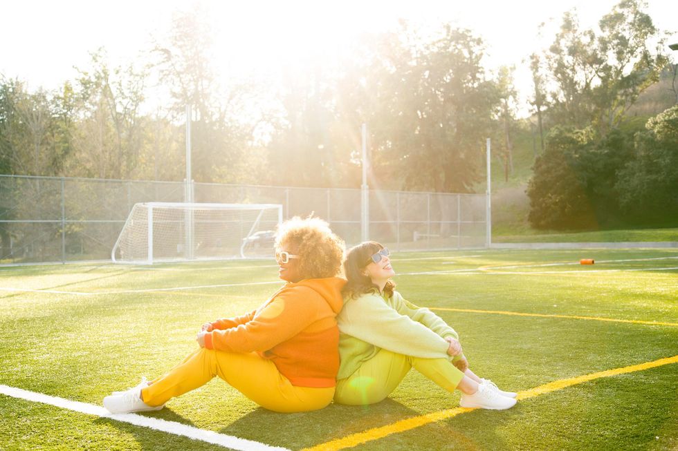 women sitting on soccer field basking in sunshine